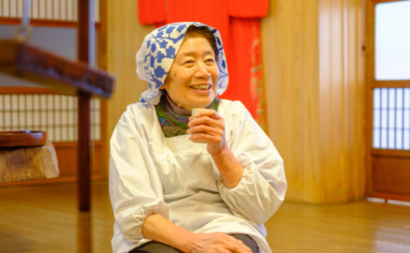 Host enjoying tea by the irori hearth