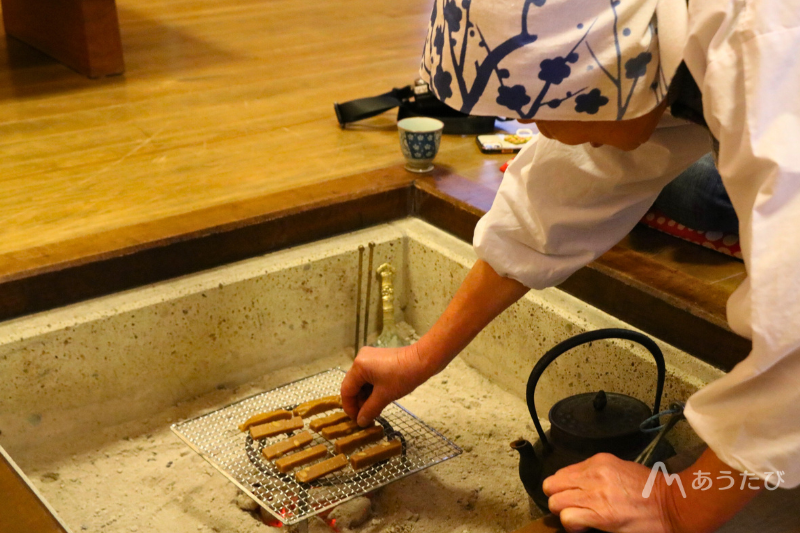 Chie grilling rice cakes over an irori hearth