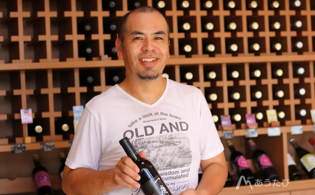 Winery president holding a wine bottle and smiling in Fukushima