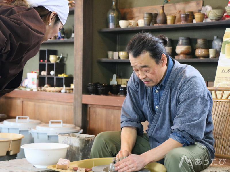 Kaneda shaping clay on a pottery wheel