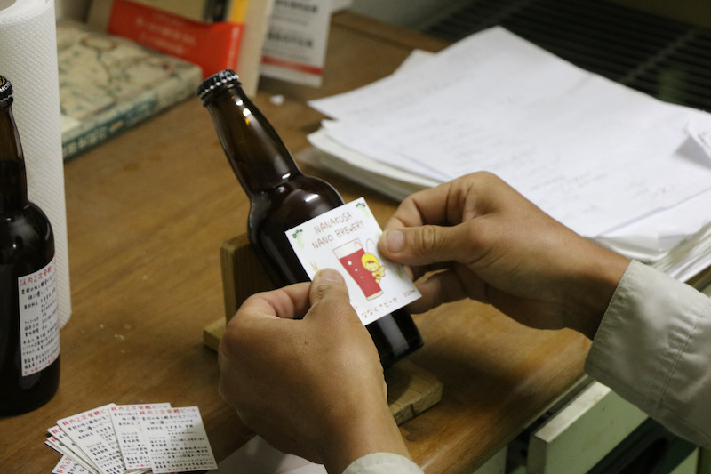 Applying labels to beer bottles by hand