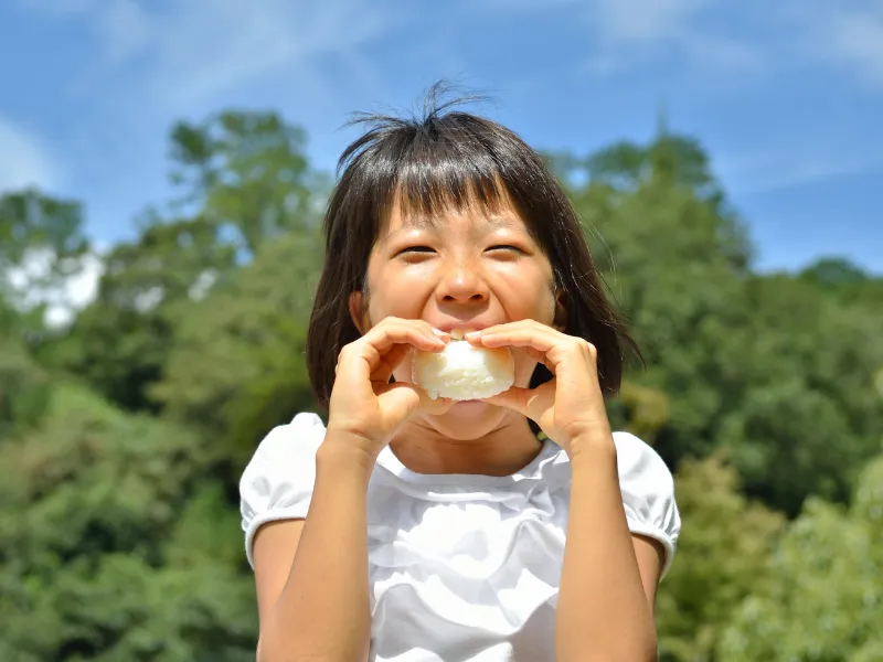 Child eating rice ball with a smile