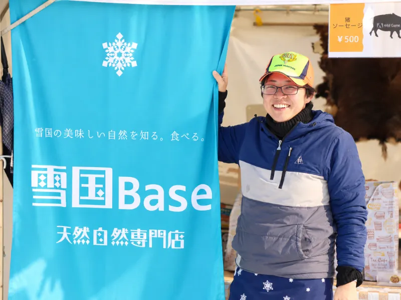 Misako Takahashi beside the Yukiguni BASE banner in Tokamachi